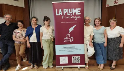 Les organisateurs de l'association La Plume & l' posant de part et d'autre d'un enrouleur publicitaire présentant leurs ateliers d'écriture créative.